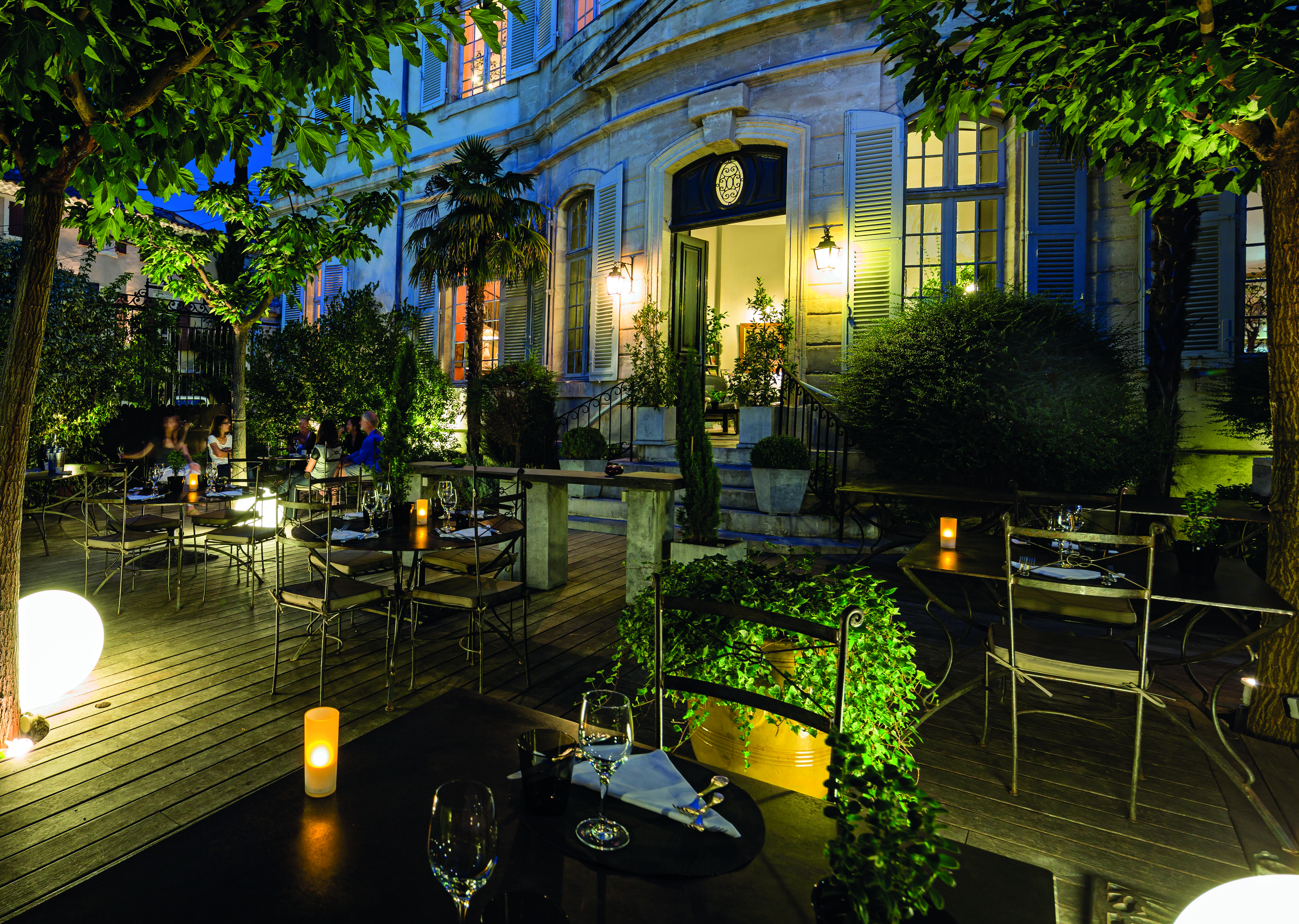 Chateau de Mazan Provence decked terrace with tables and chairs and trees at night 
