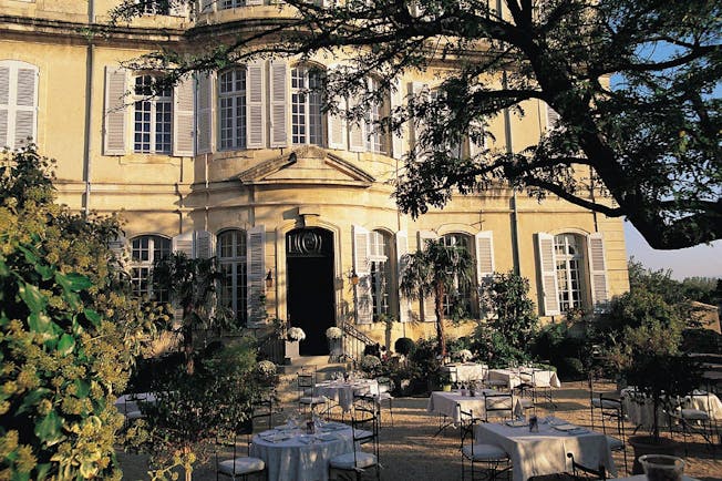 Chateau de Mazan Provence exterior terrace yellow building with shutters terraced seating area with trees and shrubs