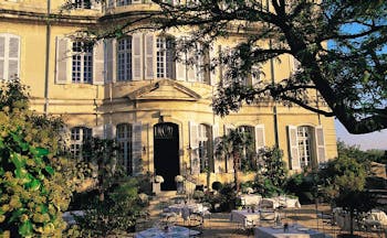 Chateau de Mazan Provence exterior terrace yellow building with shutters terraced seating area with trees and shrubs
