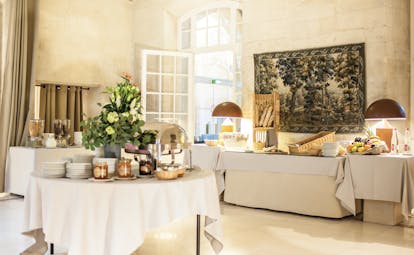 Le Cloitre Saint Louis Avignon breakfast buffet in a large stone room with a painting on the wall