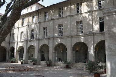 Le Cloitre Saint Louis Avignon exterior building with large arched windows and a tree