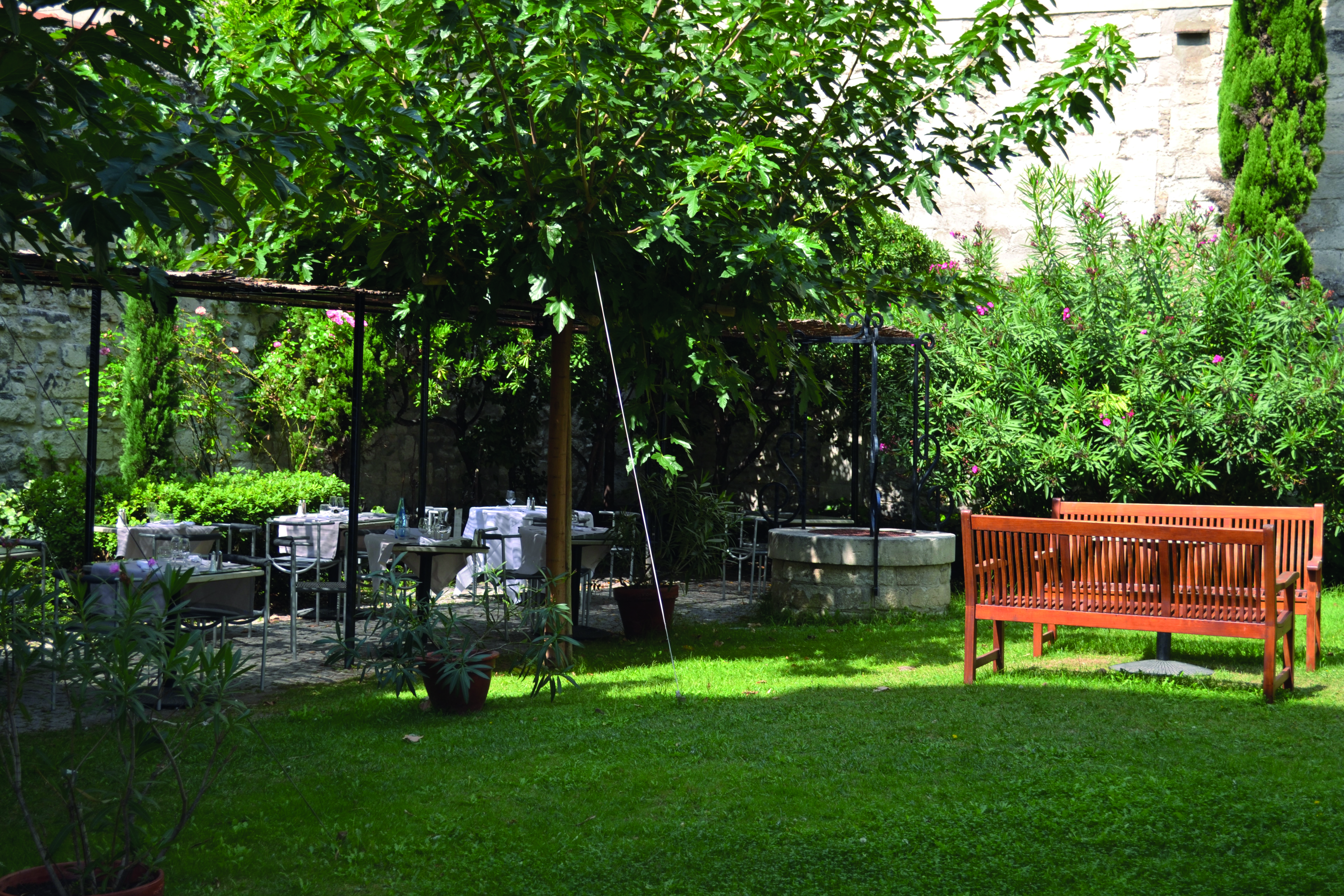 Le Cloitre Saint Louis Avignon garden with seating area and two wooden benches