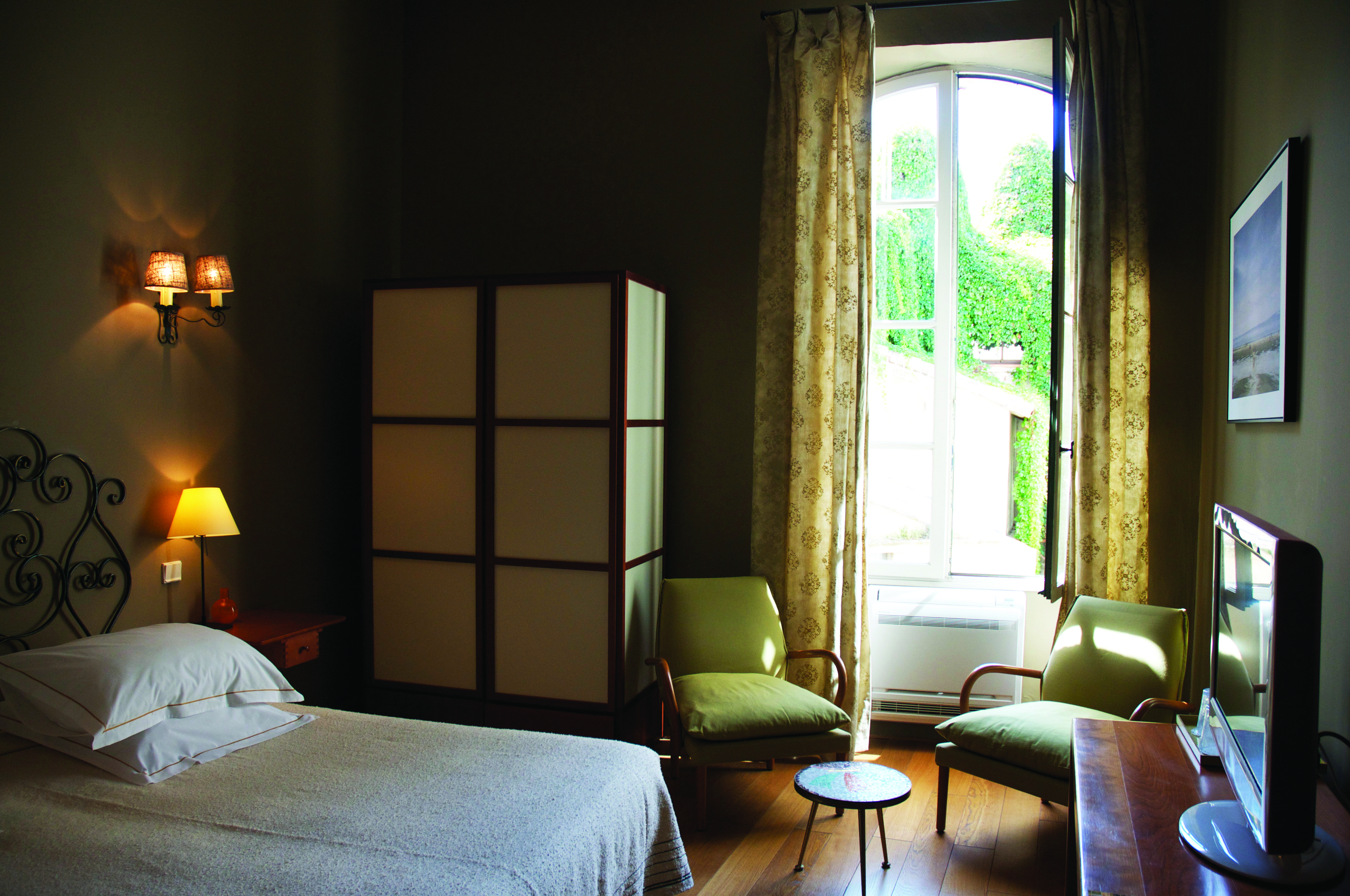 Grand Hotel Nord Pinus Provence bedroom with wrought metal head board a wardrobe television and two chairs
