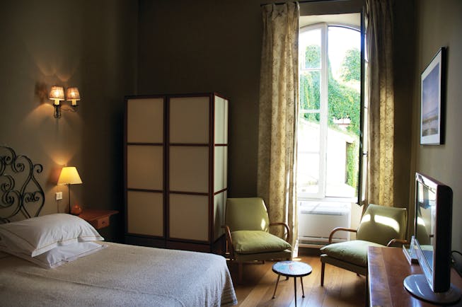 Grand Hotel Nord Pinus Provence bedroom with wrought metal head board a wardrobe television and two chairs
