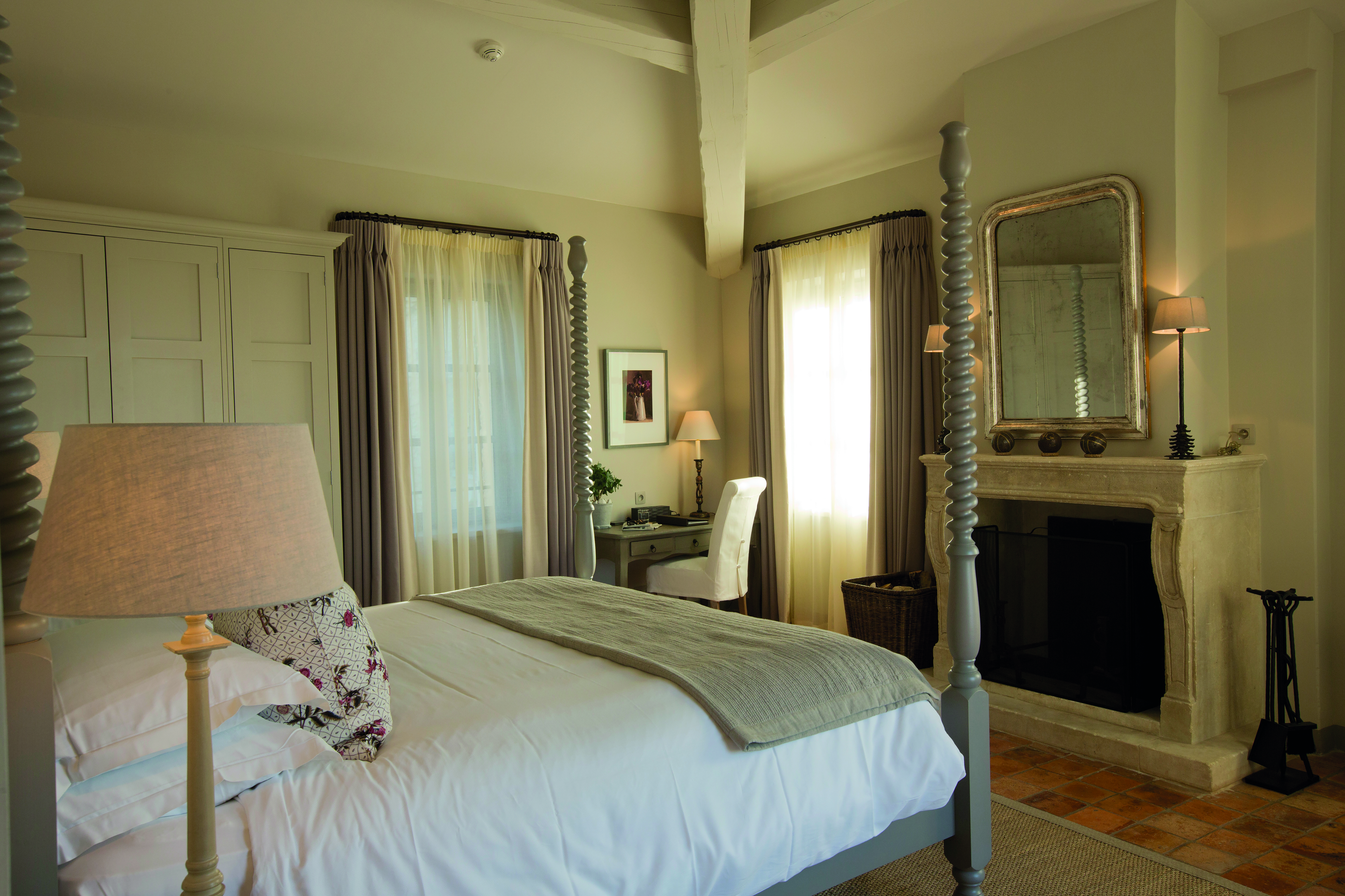 Hotel Crillon le Brave Provence bedroom with large bed with spiral posts and a large mirror over a fireplace