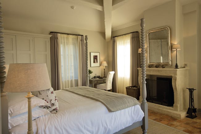 Hotel Crillon le Brave Provence bedroom with large bed with spiral posts and a large mirror over a fireplace