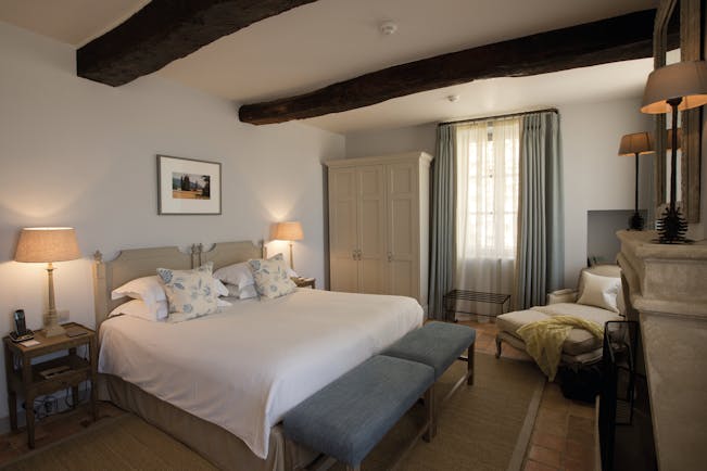 Hotel Crillon le Brave Provence bedroom with exposed beams bedside tables and lamps and an armchair