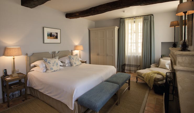 Hotel Crillon le Brave Provence bedroom with exposed beams bedside tables and lamps and an armchair