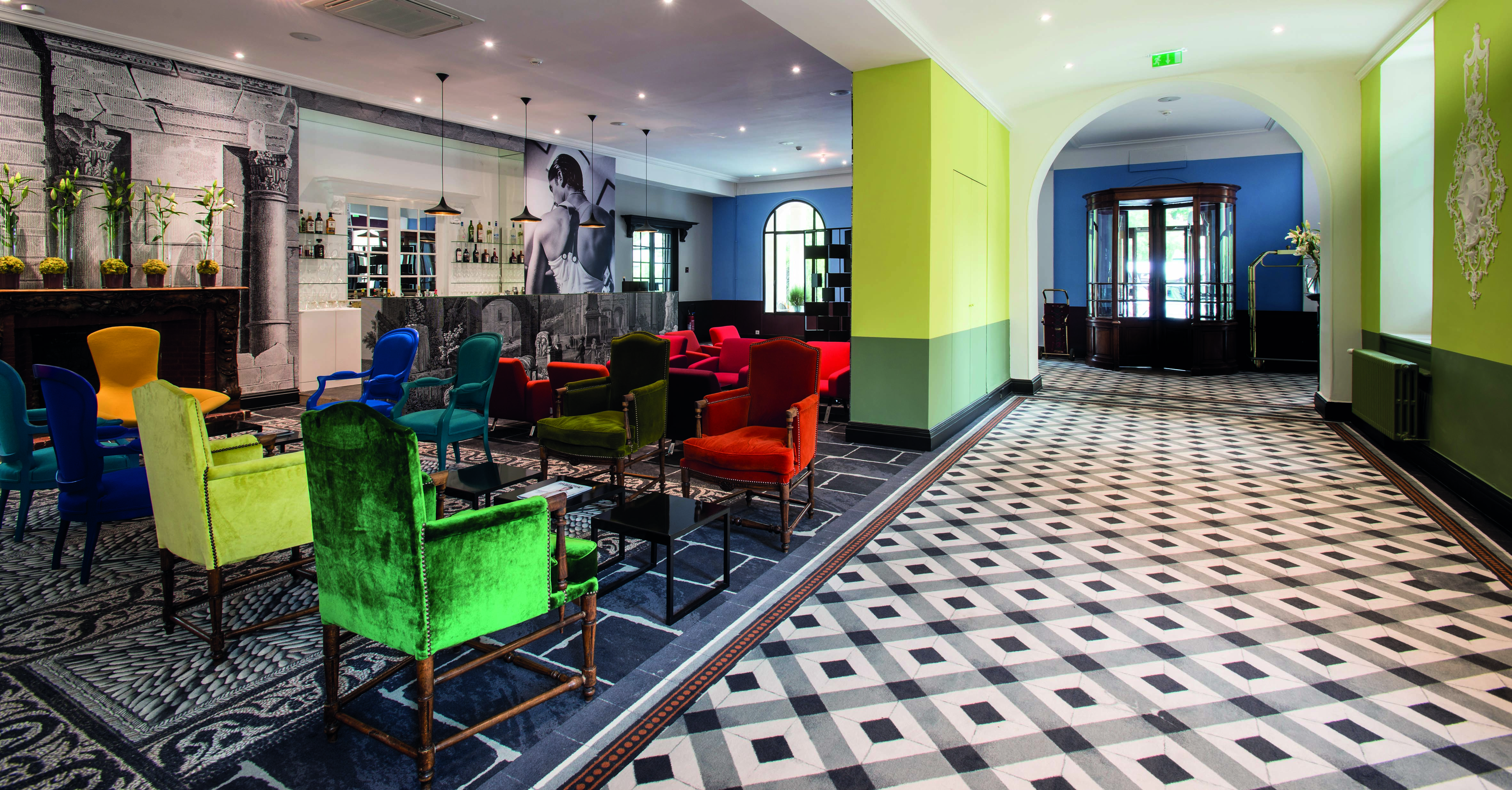 Hotel Jules Cesar Provence bar lounge tiled floor large black and white photograph and several bright chairs
