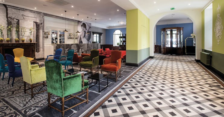 Hotel Jules Cesar Provence bar lounge tiled floor large black and white photograph and several bright chairs