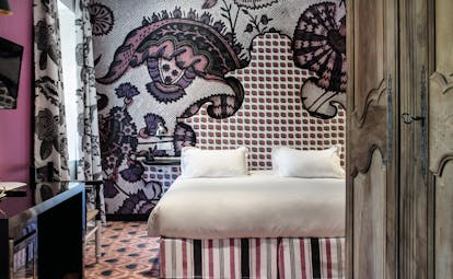 Hotel Jules Cesar Provence bedroom with one bright pink wall and one wall with graphic print patterned carpet