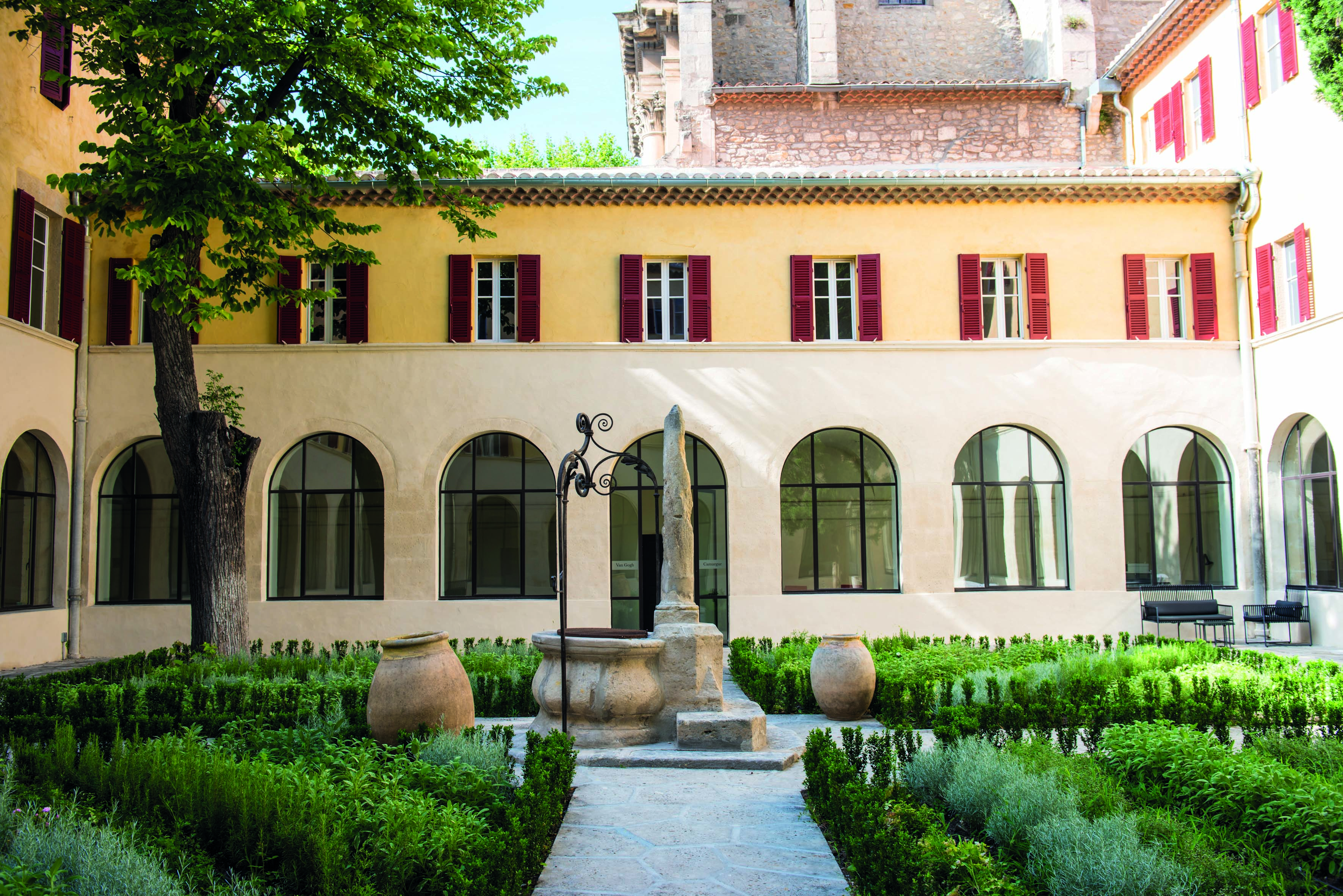 Hotel Jules Cesar Provence exterior courtyard surrounded by a building with large windows topiary and statues