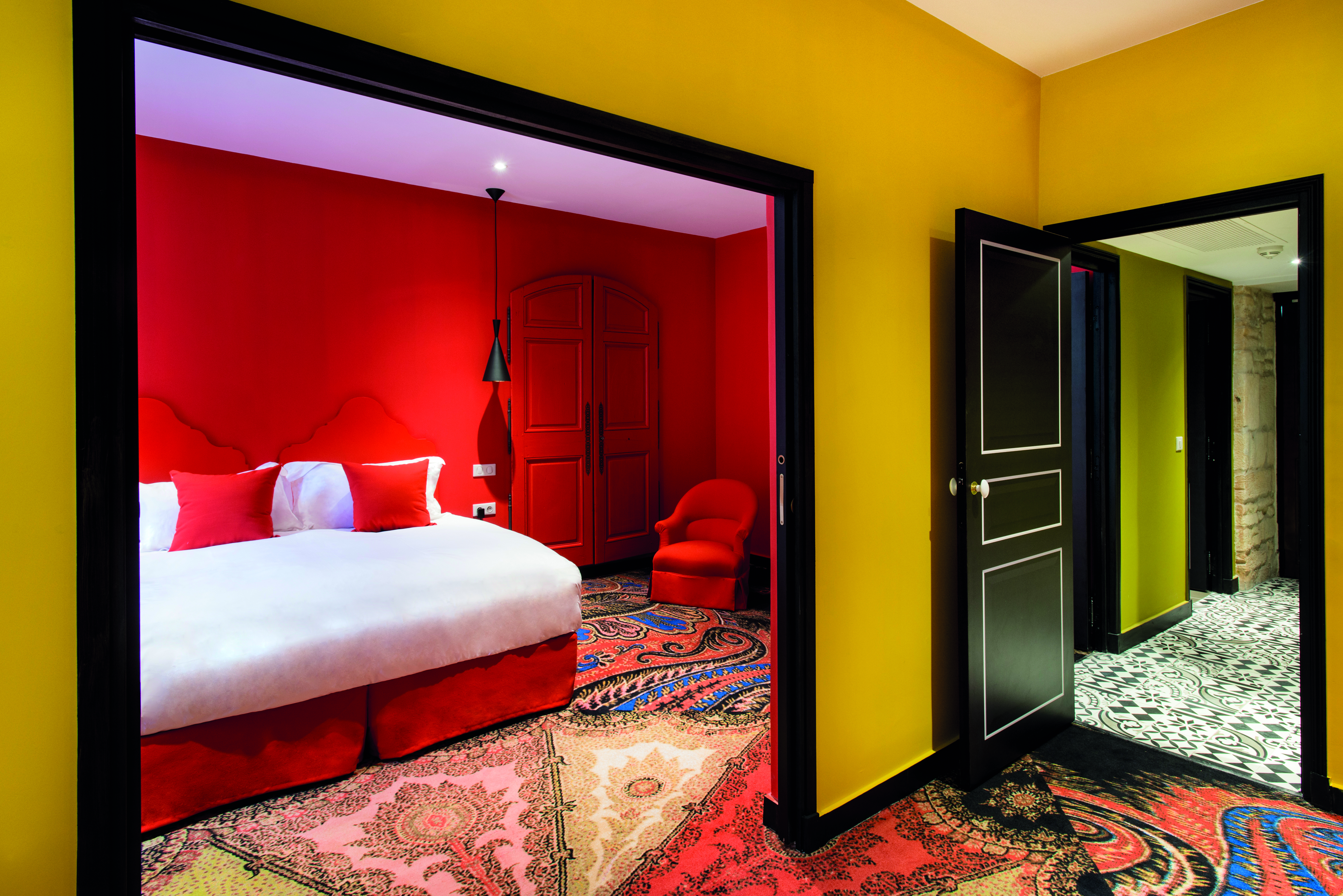Hotel Jules Cesar Provence red bedroom with archway into a room with yellow walls
