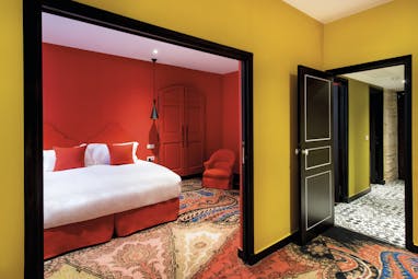 Hotel Jules Cesar Provence red bedroom with archway into a room with yellow walls