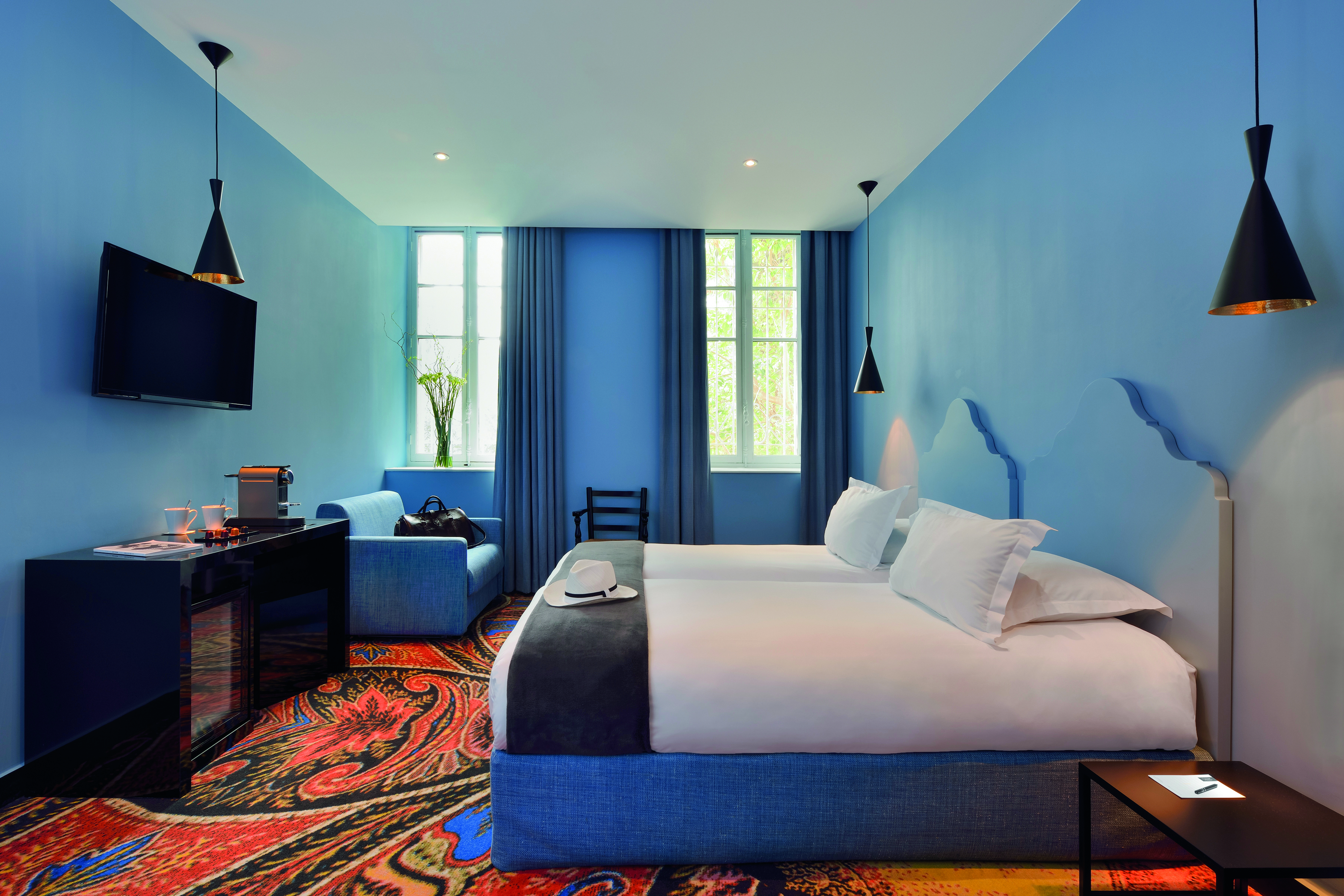 Hotel Jules Cesar Provence superior bedroom television desk sofa and a brightly coloured carpet