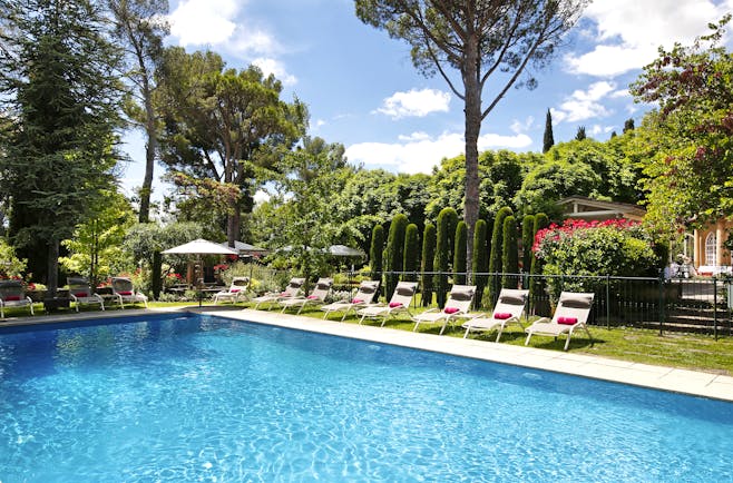 blue waters of swimming pool with trees and grass around at le pigonnet