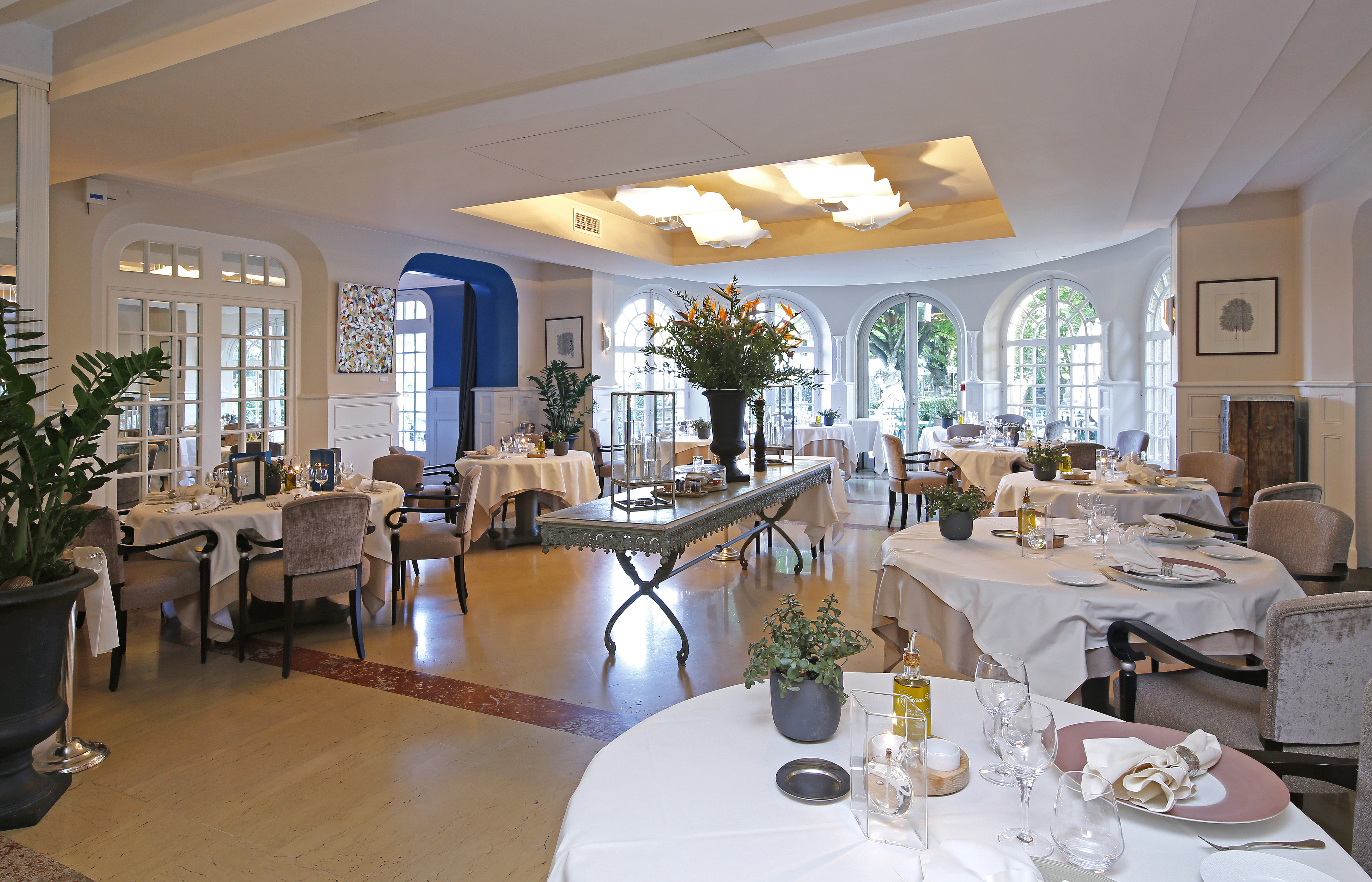 Restaurant with round white table,s wooden floor and glass windows at the pigonnet