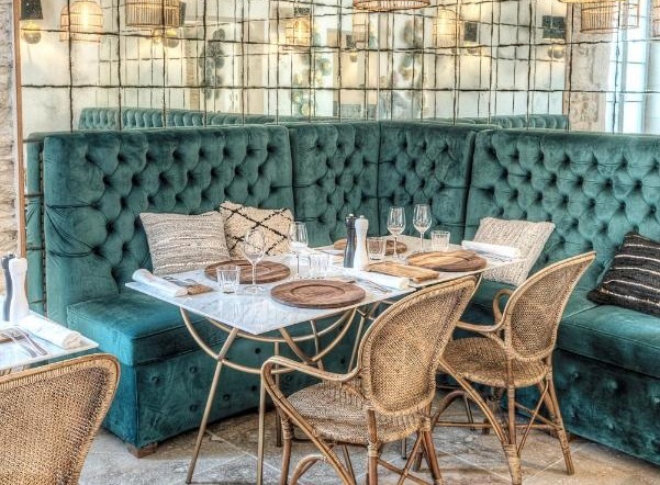 Hotel Le Saint-Remy restaurant, with mirrored walls and plush modern turquoise booths and rattan chairs