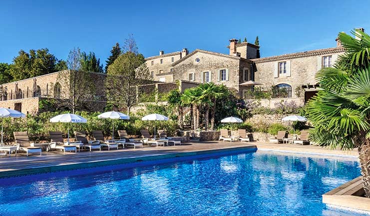 Chateau de Berne Provence exterior pool large stone building sun loungers and umbrellas