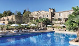 Chateau de Berne Provence exterior pool large stone building sun loungers and umbrellas