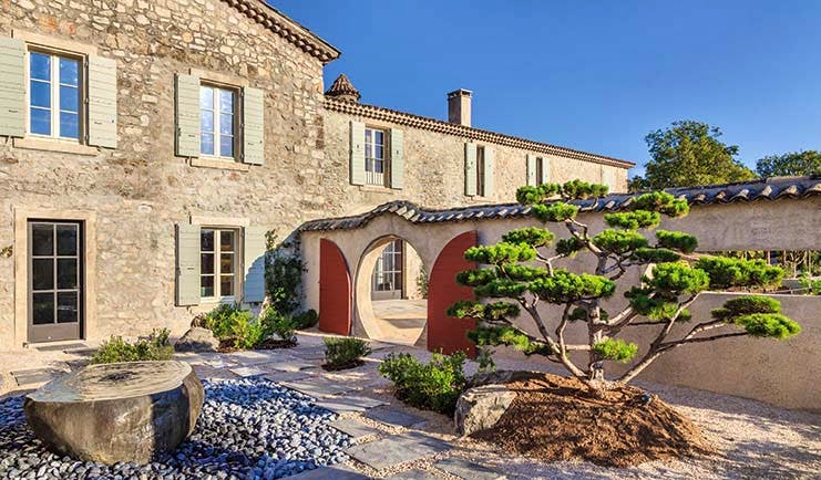 Chateau de Berne Provence exterior stone building with shutters a wall with a round door and a red gate