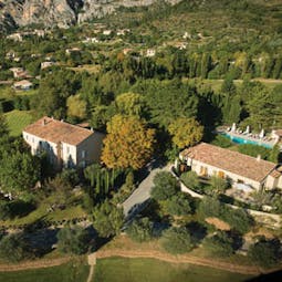 View of the hotel from above showing greenery surrounding it and swimming pool in the gardens