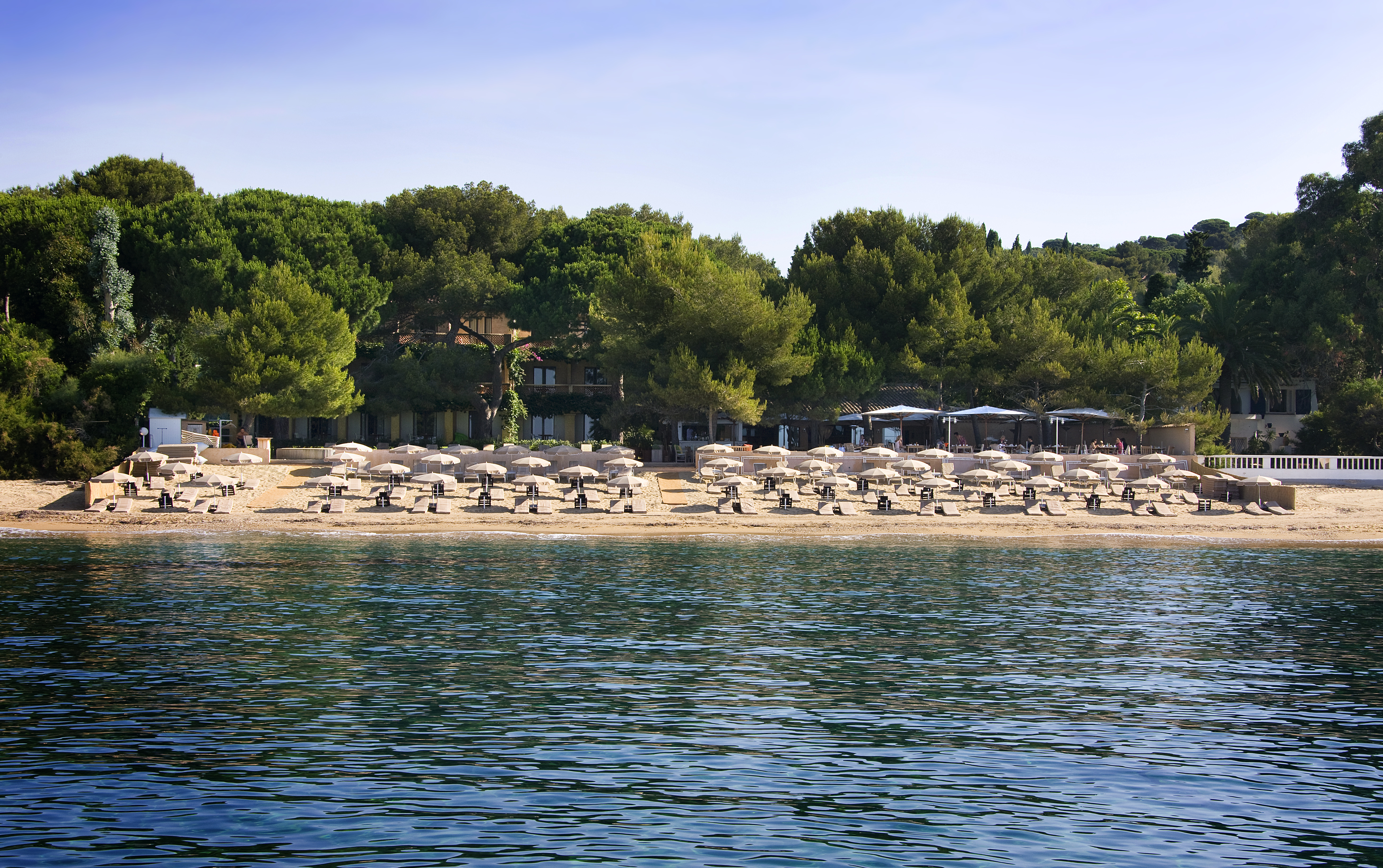 View of sandy beach with umbrellas and sun beds from sea at Pinede Plage