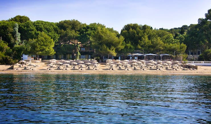 View of sandy beach with umbrellas and sun beds from sea at Pinede Plage
