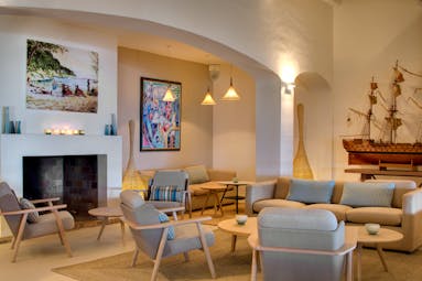 Lounge with sofas and chairs light coloured and paintings on walls and boat at La Pinede Plage