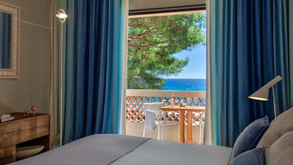 Sea facing room with balcony and blue curtains at Pinede Plage