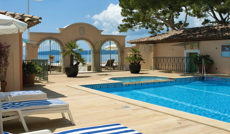 Le Club de Cavaliere Provence outdoor pool overlooking a wall with three arches and the sea