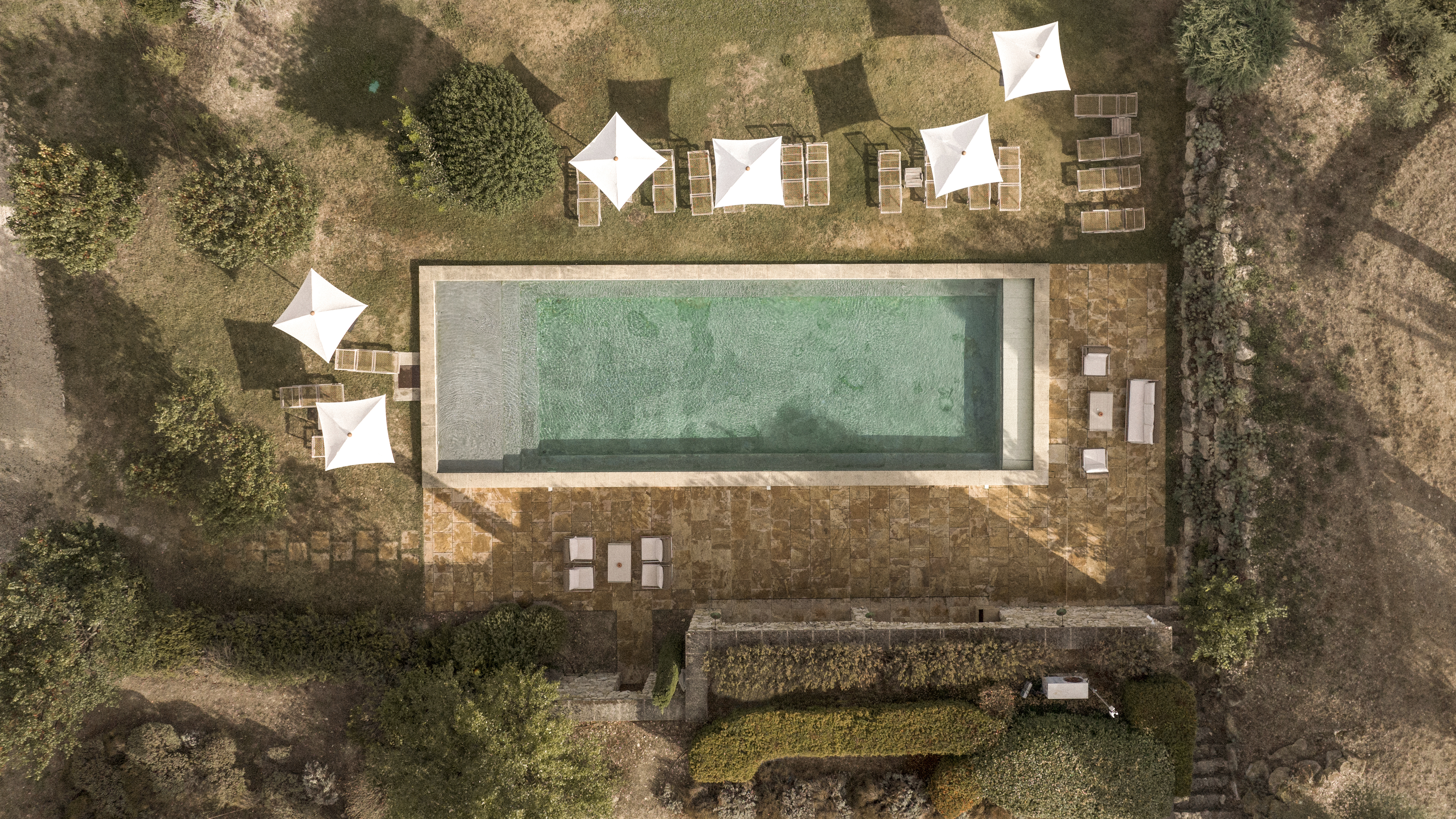Le Galinier aerial view of the swimming pool, with white parasols by the side