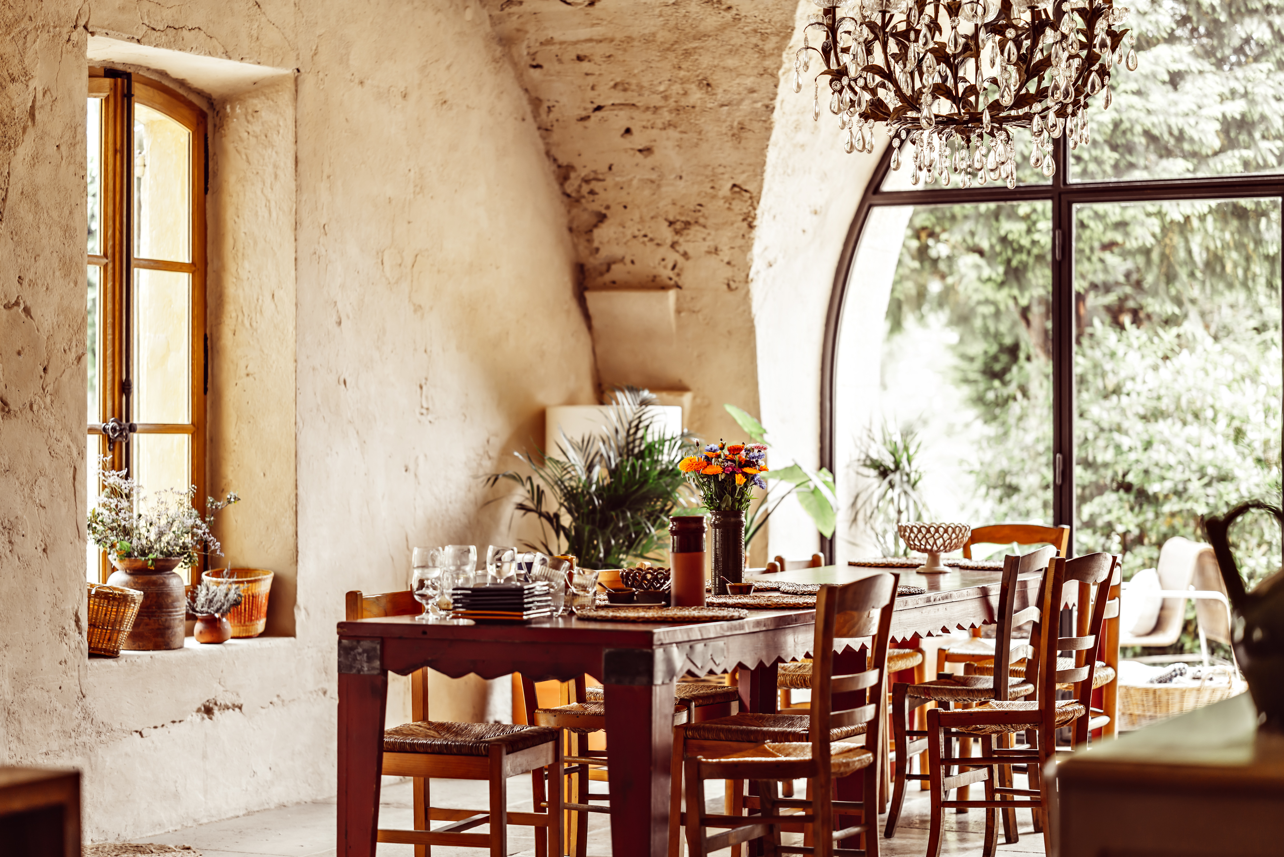 Le Galinier Wooden restaurant table in a stone-walled room with large arched window