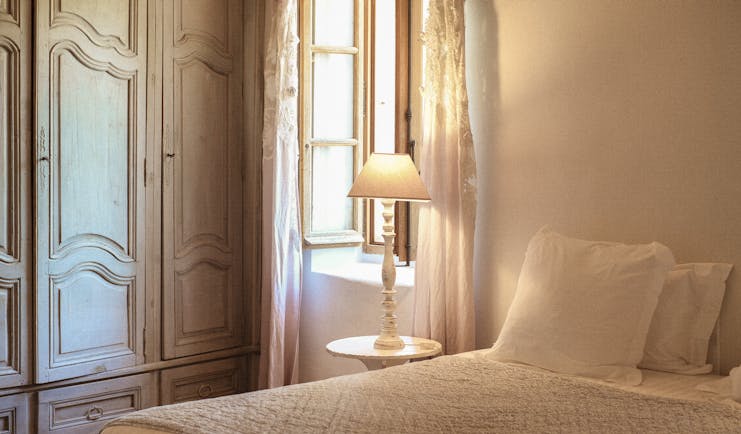 Le Galinier white bedroom with lamp and open wooden-framed window