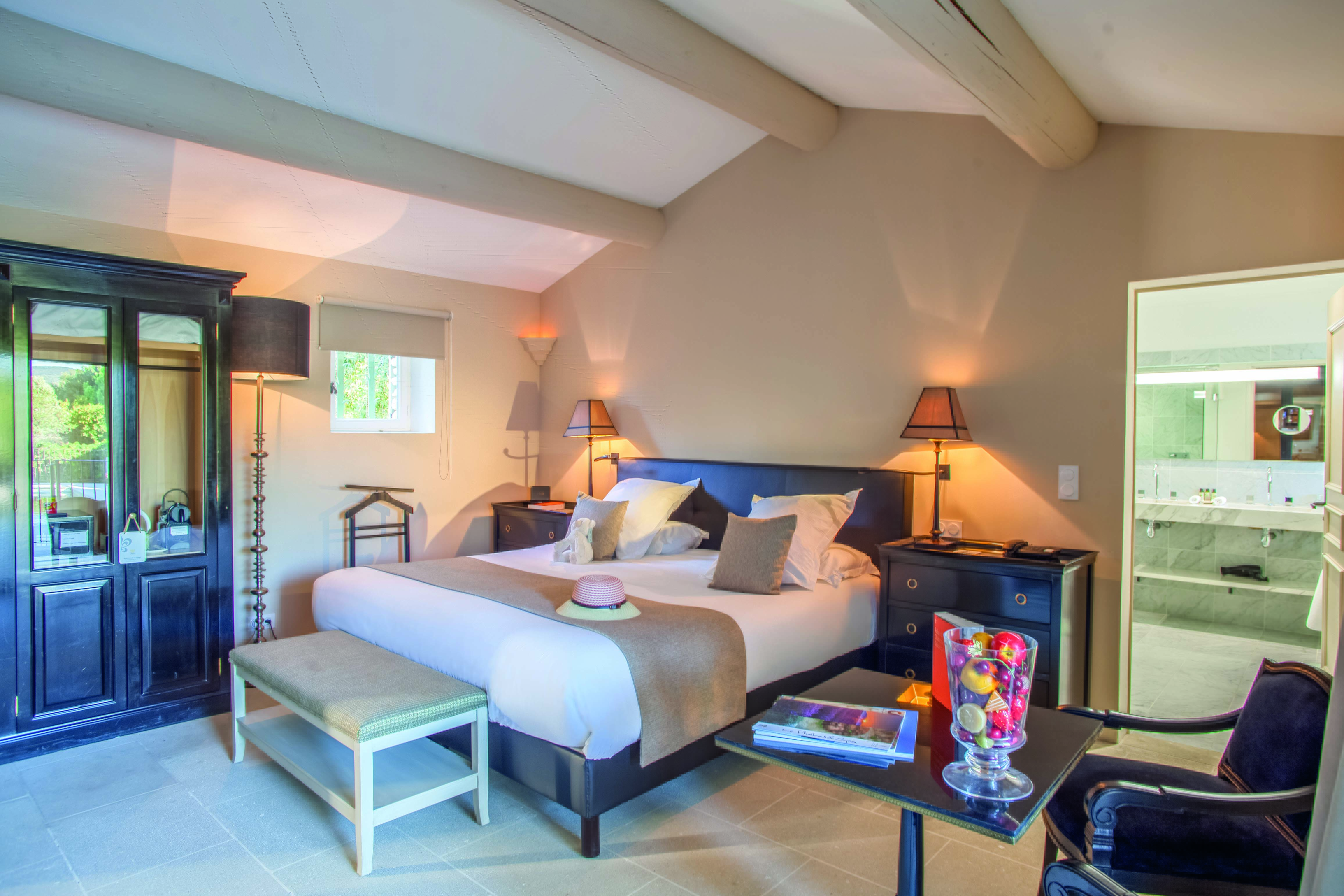 Bedroom with view of bathroom, showing double bed, chairs, bed-side table and bathroom sink