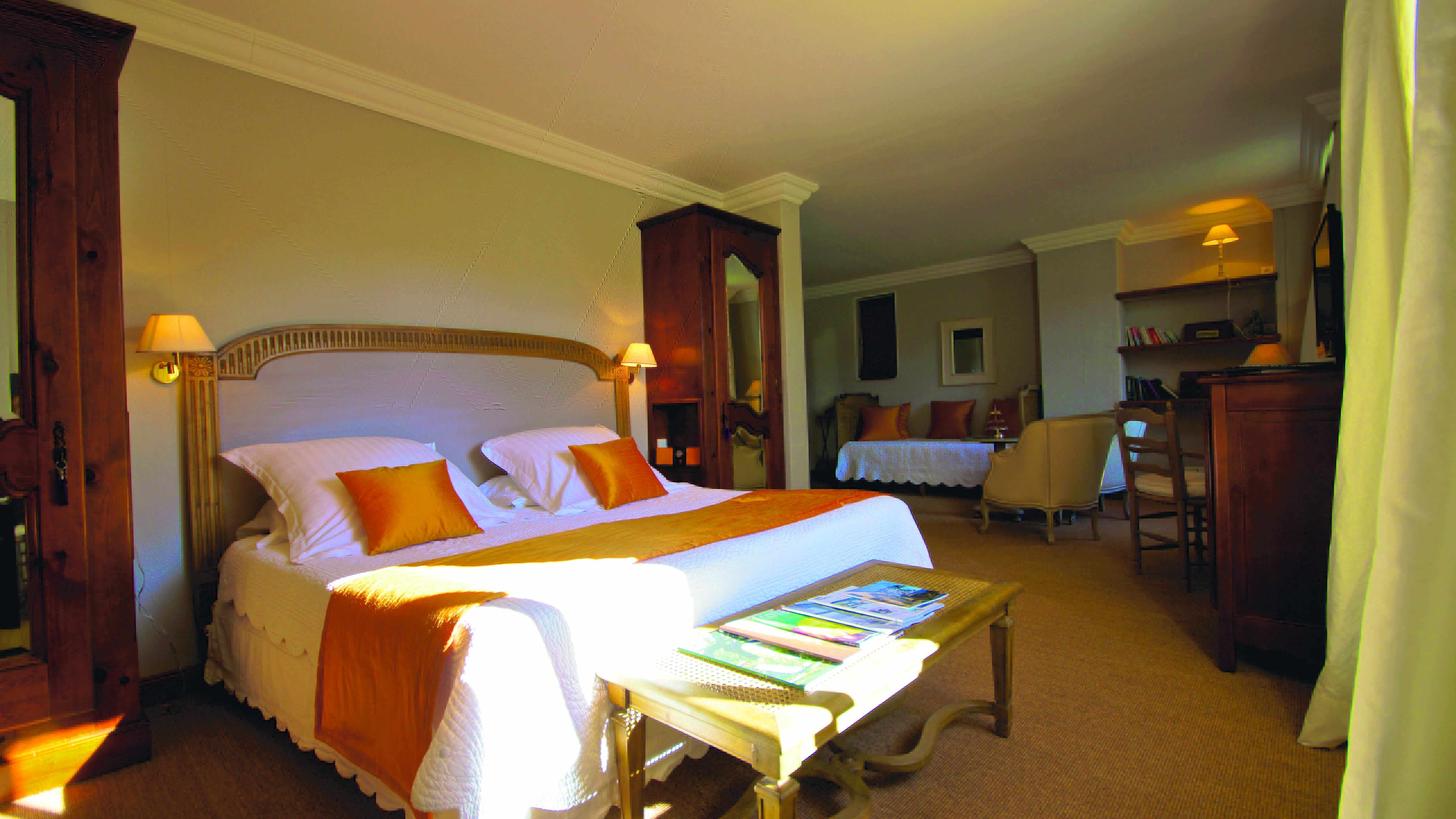 Large room with bed, seating areas and wooden storage units