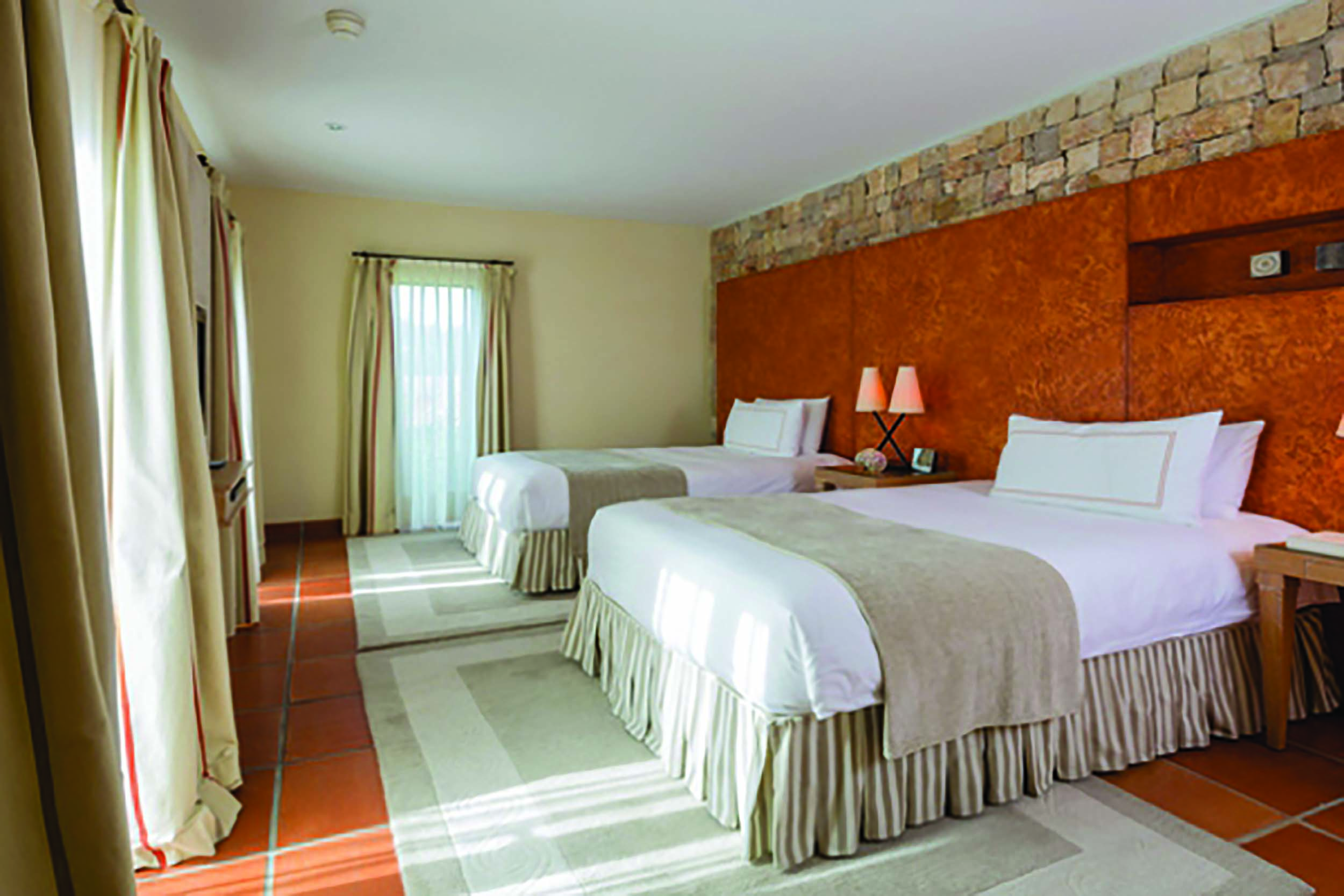 Terre Blanche Hotel and Spa Provence premier suite bedroom with two large beds orange wall and lamps
