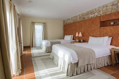 Terre Blanche Hotel and Spa Provence premier suite bedroom with two large beds orange wall and lamps