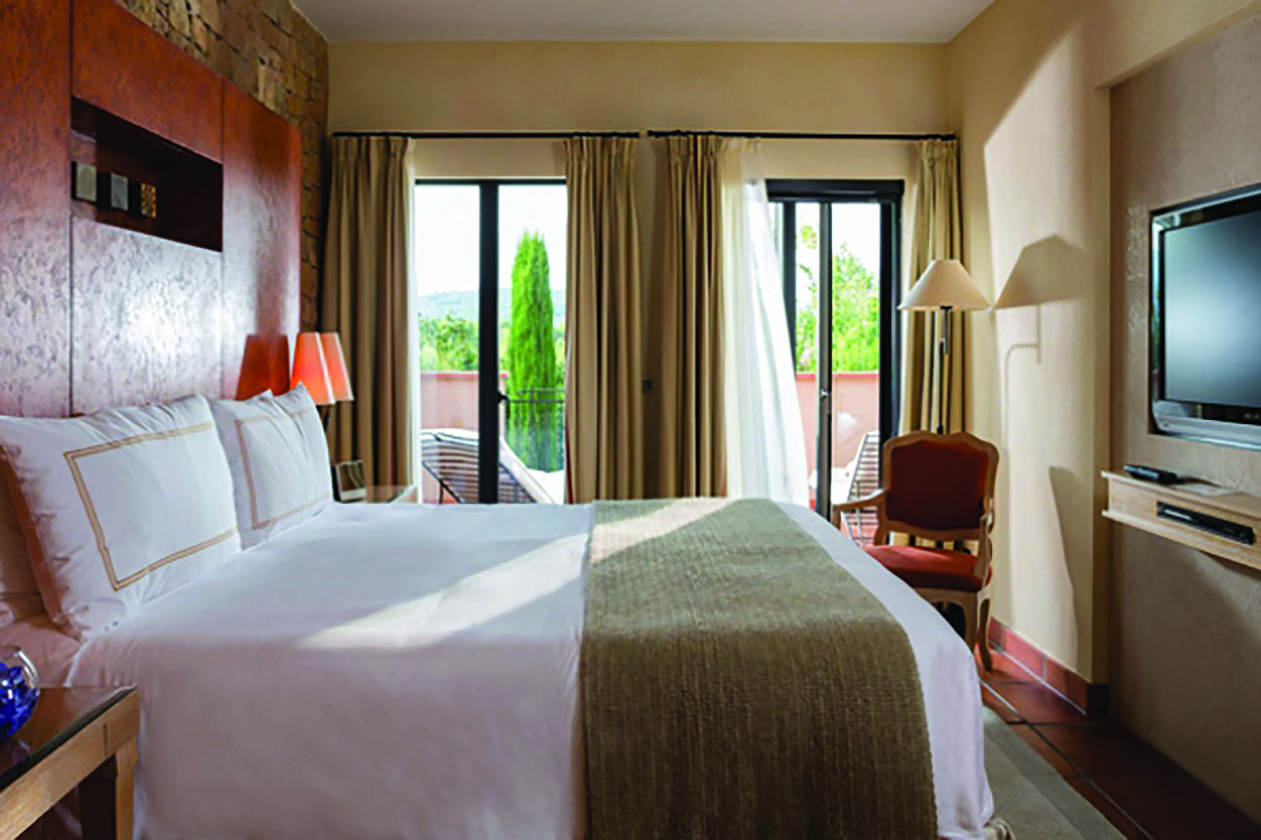 Terre Blanche Hotel and Spa Provence premier villa bedroom with chair and glass door onto a balcony
