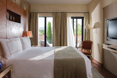 Terre Blanche Hotel and Spa Provence premier villa bedroom with chair and glass door onto a balcony