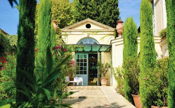 Villa Gallici Provence entrance path with topiary trees and potted plants leading to a building