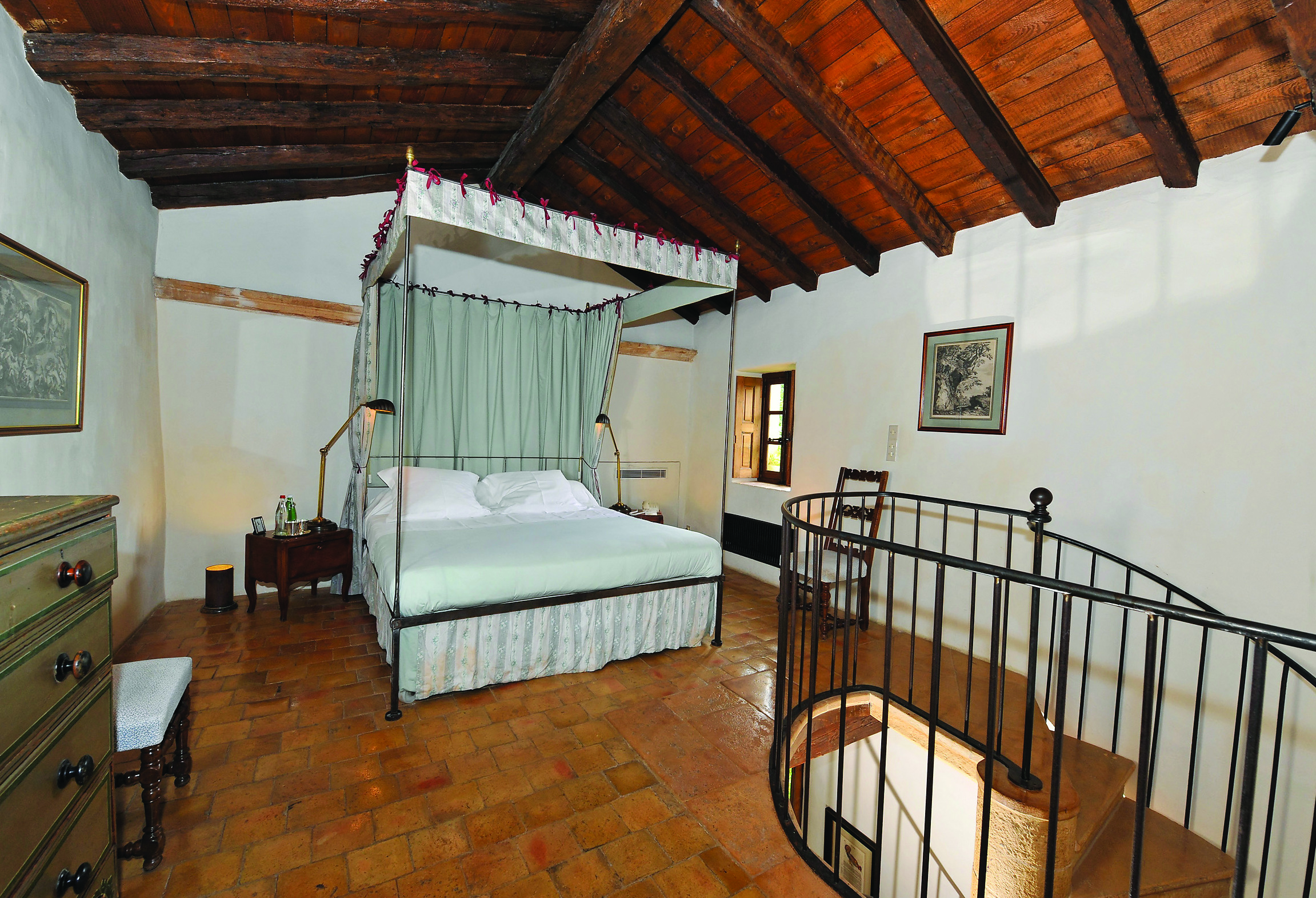 Chateau de Bagnols Rhone Valley bedroom with a four poster bed with drapes and tapestry on the wall