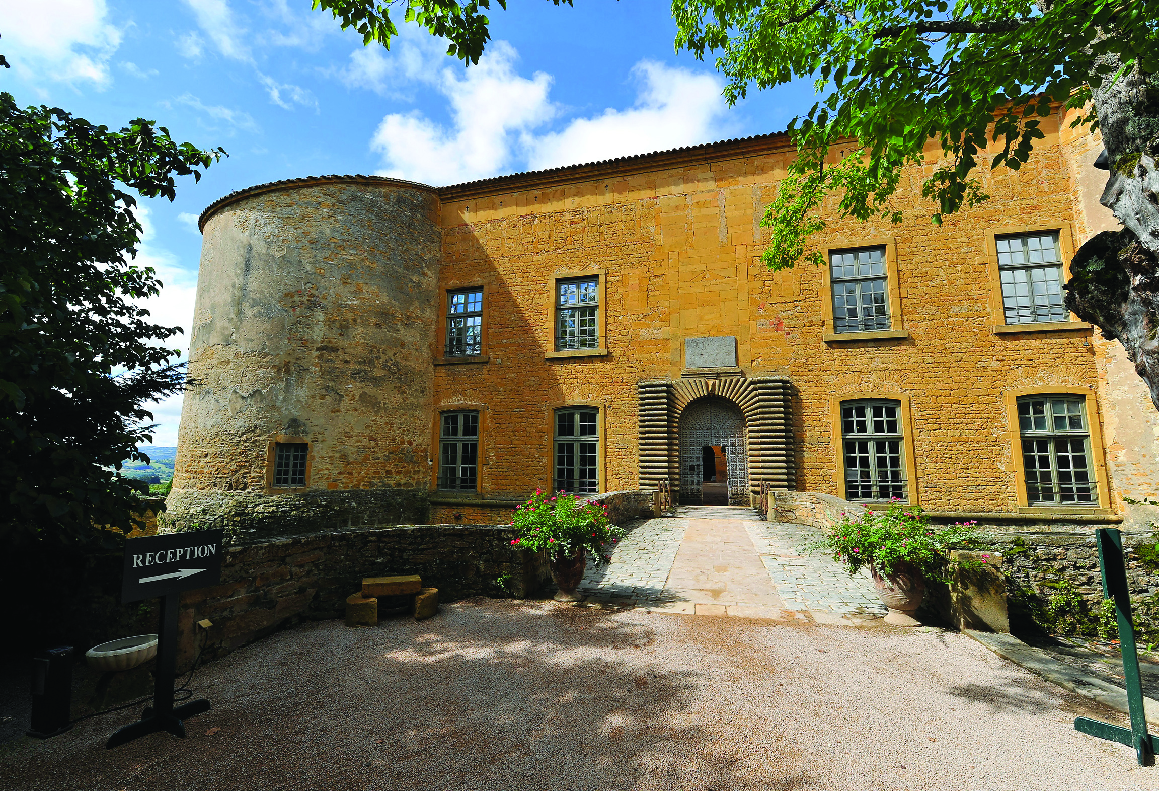Chateau de Bagnols Rhone Valley exterior moat yellow chateau with round turret and stone bridge over an empty moat
