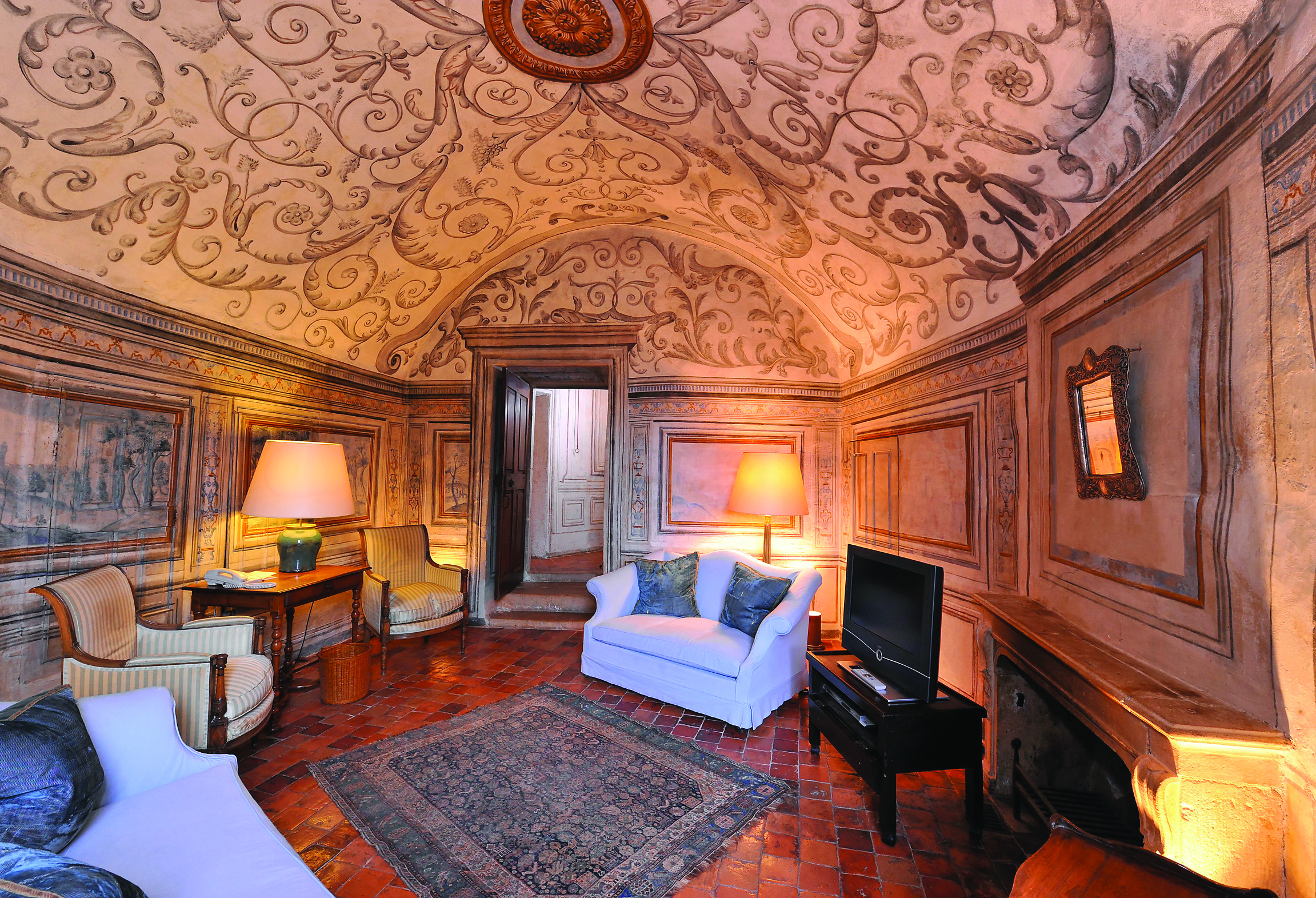 Chateau de Bagnols Rhone Valley suite lounge area with painted ceiling sofas armchair desk and fireplace