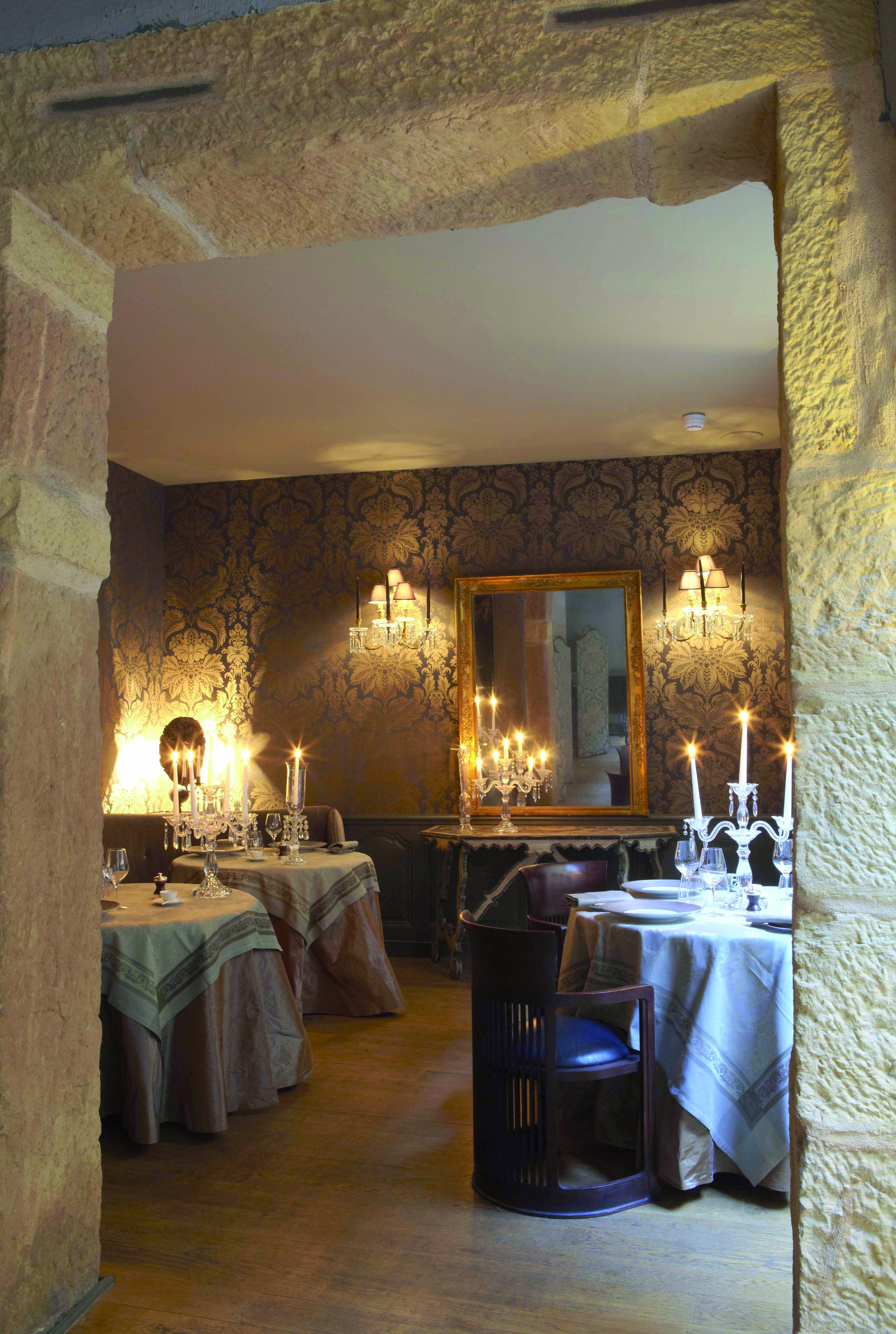 Hotel Cour des Loges Lyon dining area with three round tables with candelabras and a large mirror