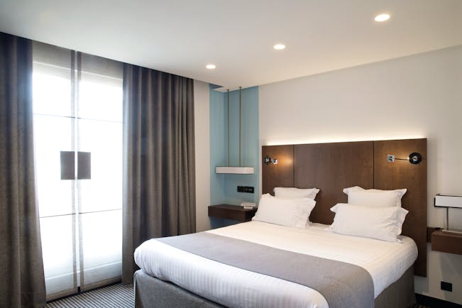Room at the Hotel la Pyramide with double bed, bed side tables and large windows