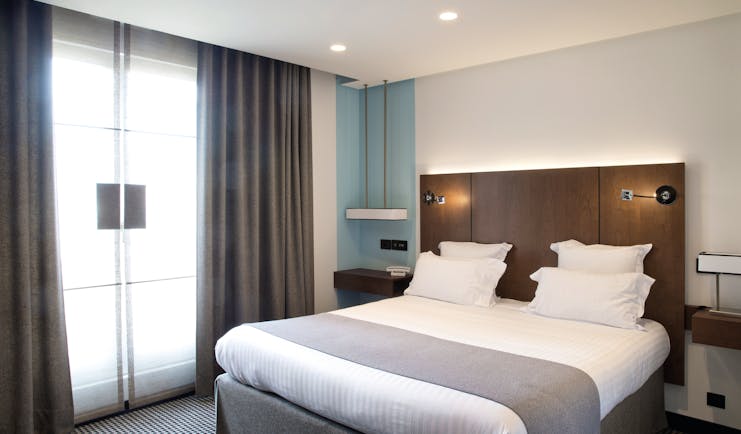 Room at the Hotel la Pyramide with double bed, bed side tables and large windows