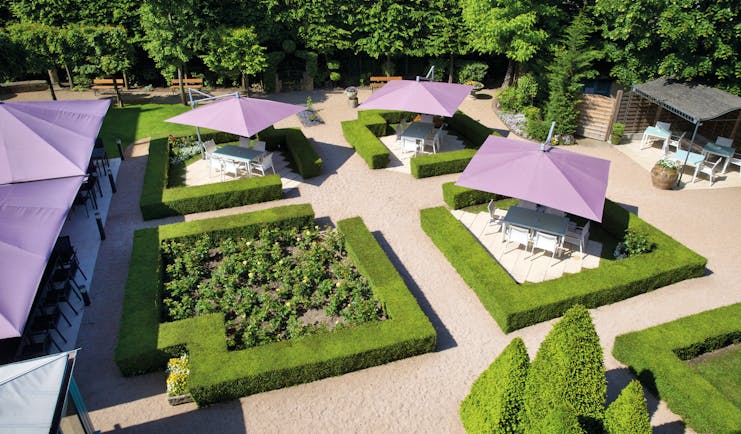 Aerial view of the gardens, showing freshly trimmed bushes and purple umbrellas