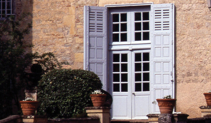 Chateau de Mercues Tarn and Lot shutters stone building with blue door with shutters and shrubbery