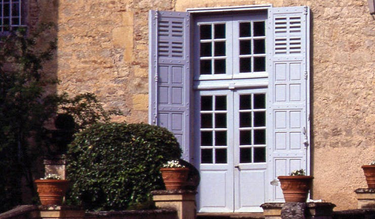 Chateau de Mercues Tarn and Lot shutters stone building with blue door with shutters and shrubbery